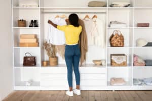 black woman choosing clothes in wardrobe back to camera indoor